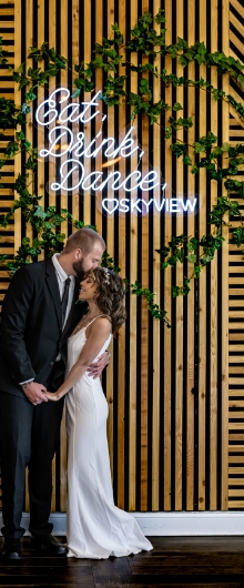Eat. Drink. Dance. Couple posing under lit sign at SkyView Golf Club in New Jersey.