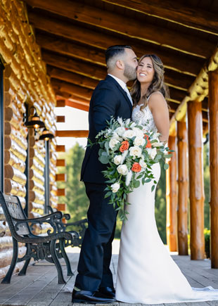 Groom kissing smiling bride on cabin porch at SkyView Golf Club in New Jersey.